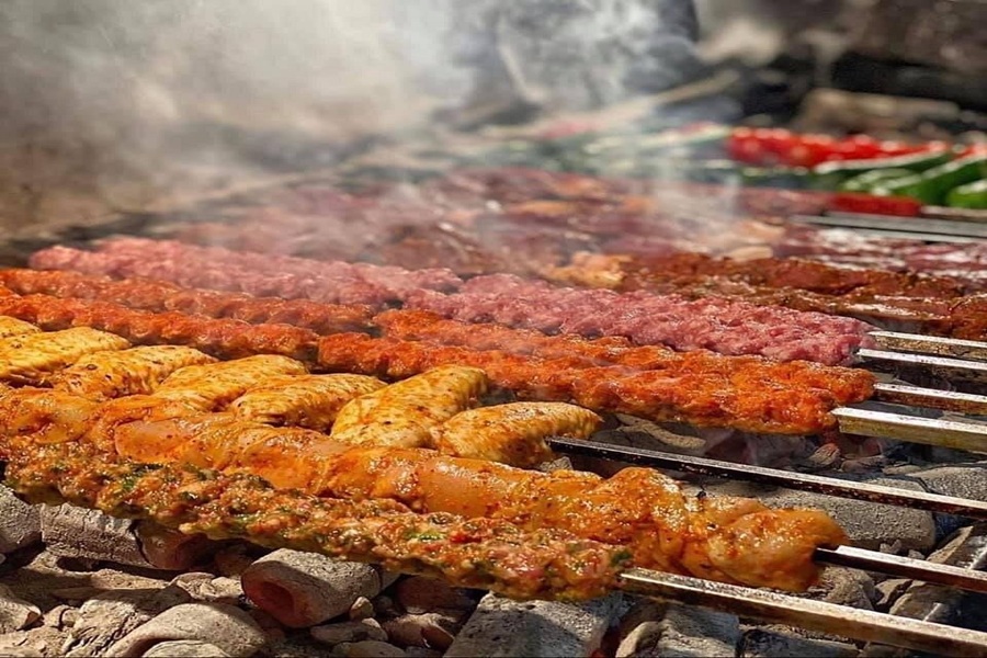 Grilled skewers with marinated meats and vegetables over open flames, evoking outdoor barbecue flavors.