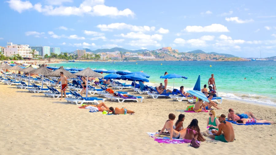 Beachgoers relax and play at a sunny, vibrant Playa d’en Bossa, Ibiza.