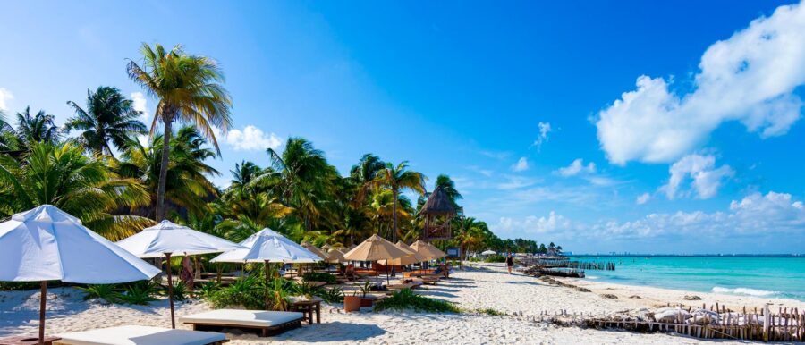 Tropical beach paradise with white sand, turquoise ocean, palm trees, and beach loungers.