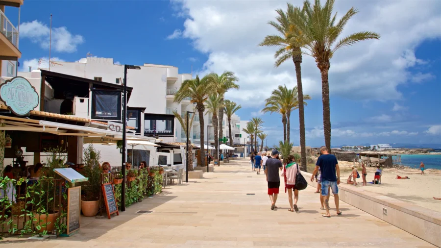 Formentera promenade with palm trees, white cafes and turquoise Mediterranean sea.