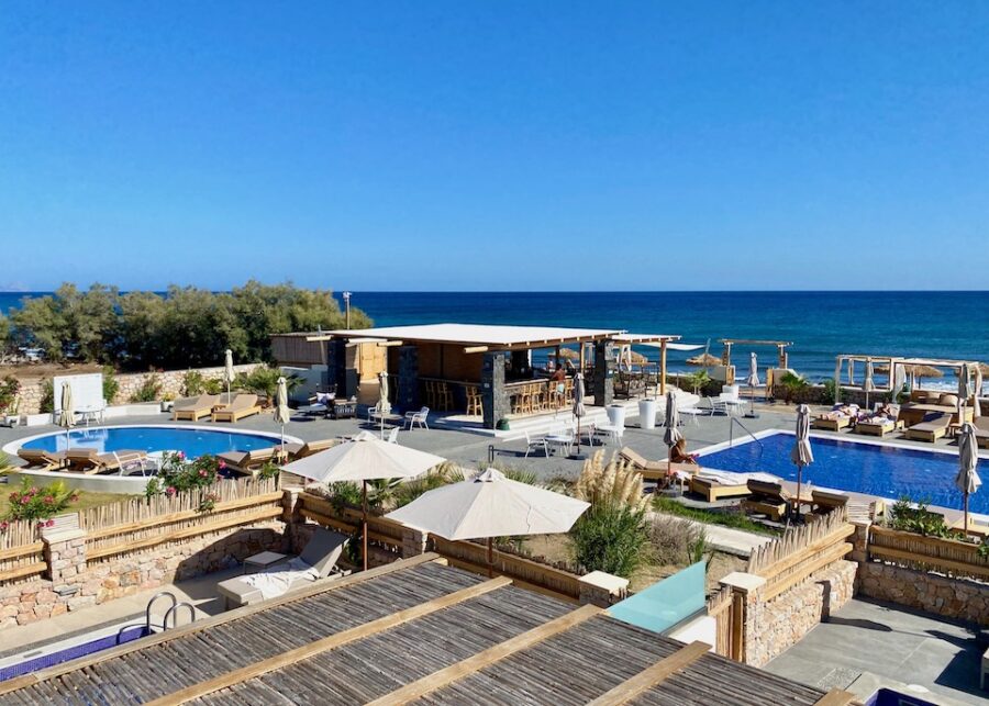 Santorini beach resort with pool, lounge chairs, sea view, and bar for family relaxation.