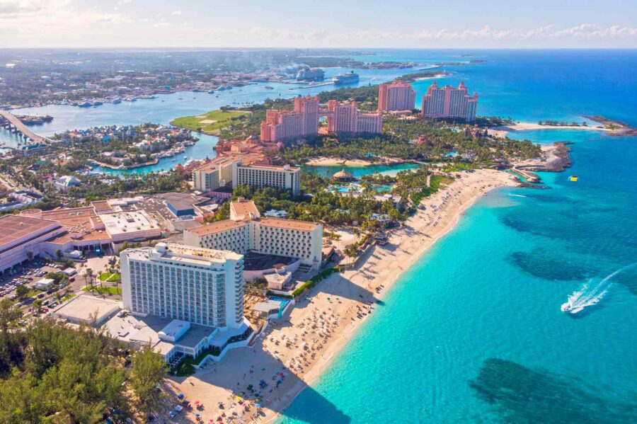 Aerial view of Bahamas resort: turquoise waters, white sand beaches, luxury hotels, palm trees.