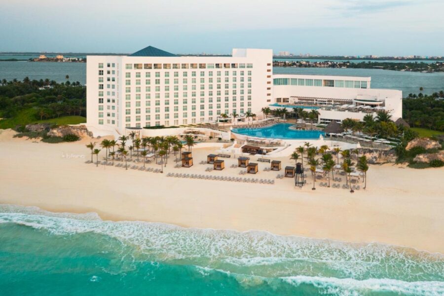 Luxury beachfront resort with palm trees, pool, and turquoise ocean in tropical paradise.