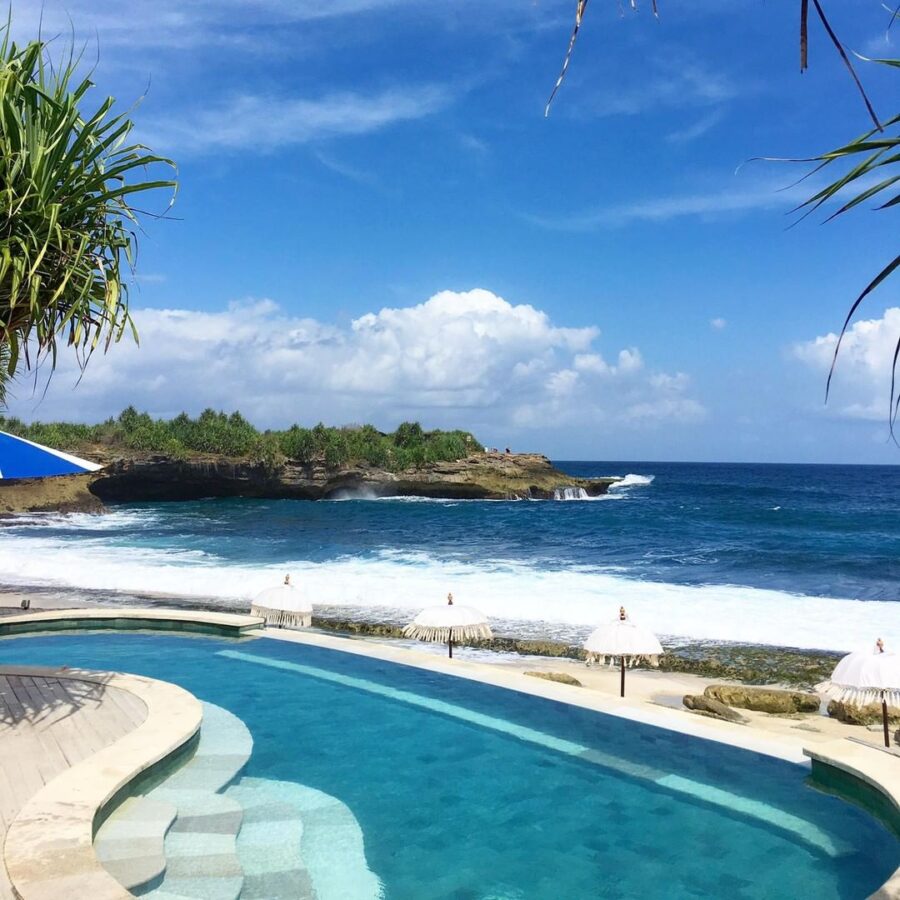 Luxury beachfront infinity pool overlooking turquoise ocean waves at tropical Sandy Bay Beach Club resort.