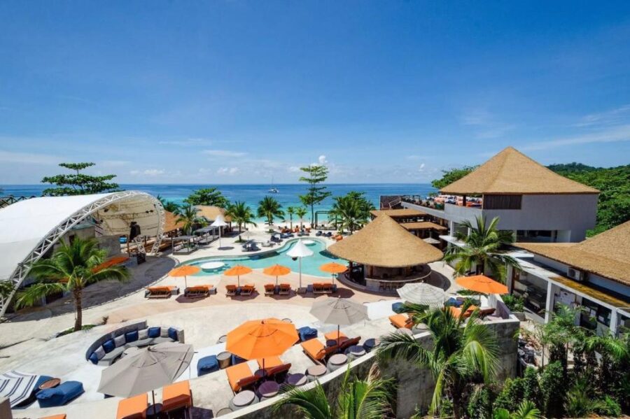 Tropical beachfront luxury resort with infinity pool, sun loungers, palm trees, and ocean views.