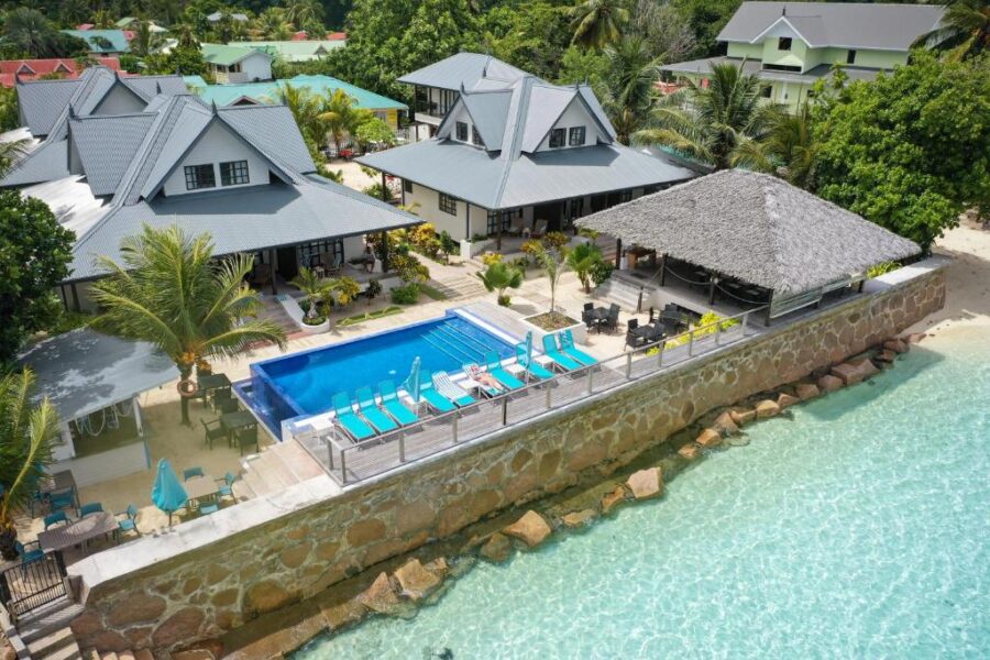Luxury beachfront resort with infinity pool, turquoise ocean, tropical villas, and seaside restaurant pavilion.
