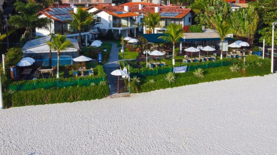 Beachfront resort with private sandy beach access, palm trees, solar-roof villas and lounge umbrellas.
