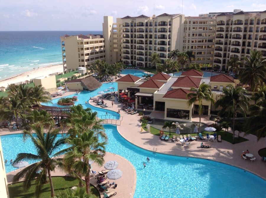 Tropical beachfront resort with pool, palm trees, and ocean views in Cancún, Mexico.
