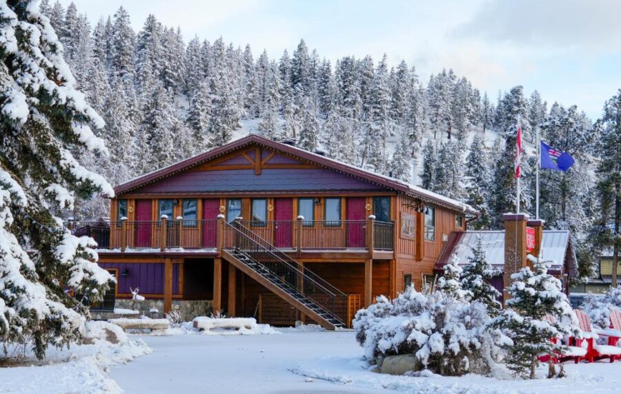 Bear Hill Lodge in Jasper, Canada, surrounded by tall, snow-covered trees under a clear blue sky.
