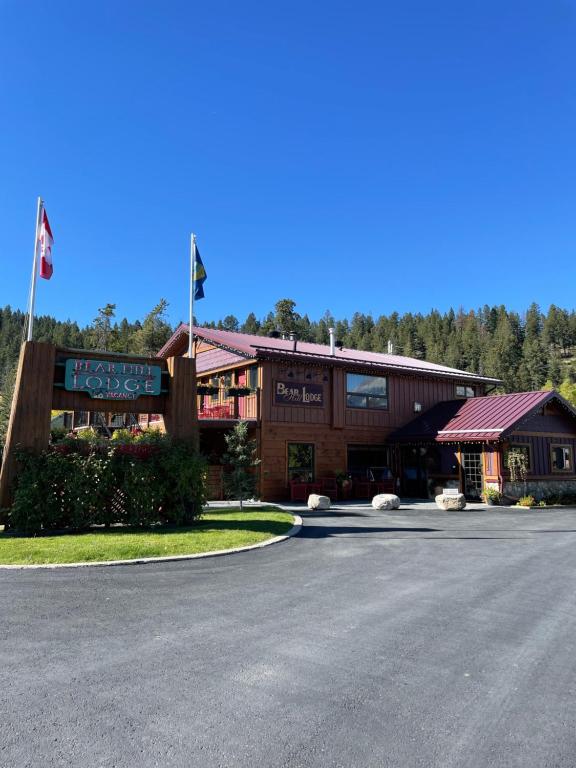 Bear Hill Lodge in Jasper, Canada, showcasing a rustic wooden exterior surrounded by lush greenery and mountains.
