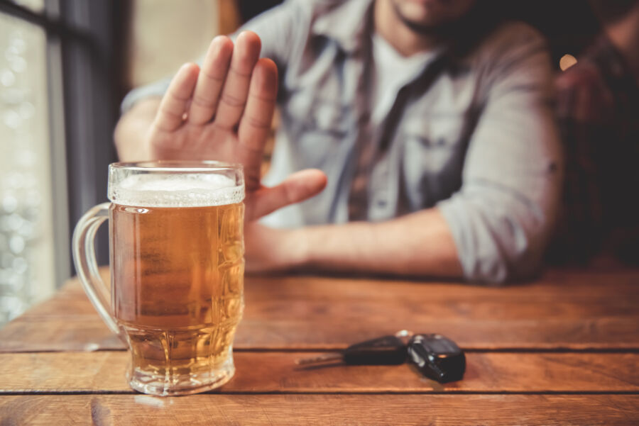 Man in a pub turns down a beer, clutching his car keys, highlighting the importance of not drinking and driving 