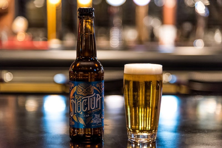 Craft beer Noctua pale ale bottle and glass at a cozy bar counter.