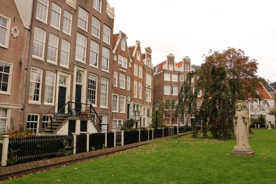 Scenic view of Begijnhof in Amsterdam with a prominent statue, showcasing the serene atmosphere and historic buildings.