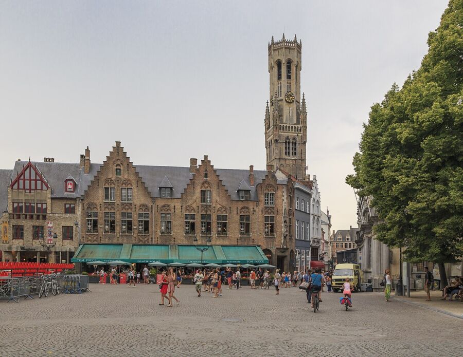 The Belfry of Bruges, a historic clock tower, rises above surrounding buildings in a picturesque cityscape.