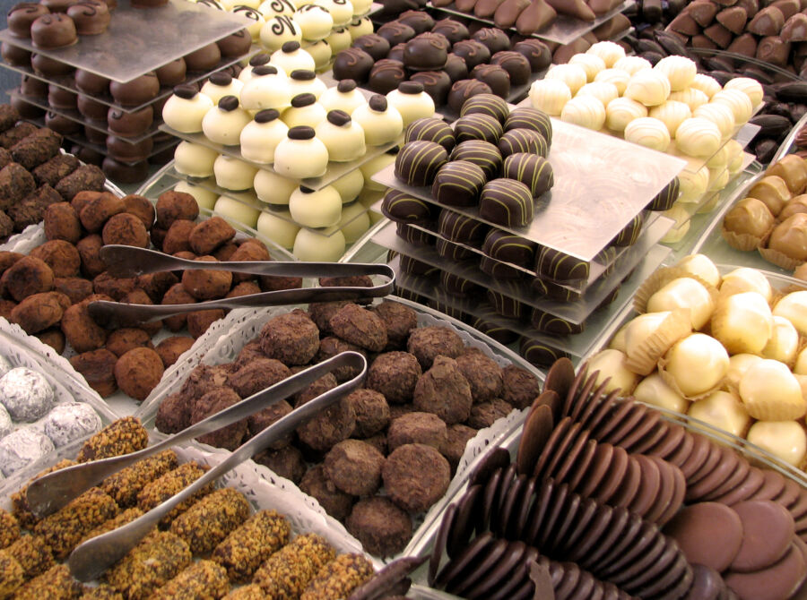 Close-up of assorted Belgian chocolates showcasing various shapes and textures on a dark background.