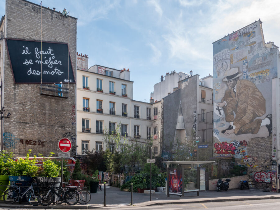 Colorful street art murals cover building facades on rue Belleville, Paris, highlighting the city's urban artistic culture