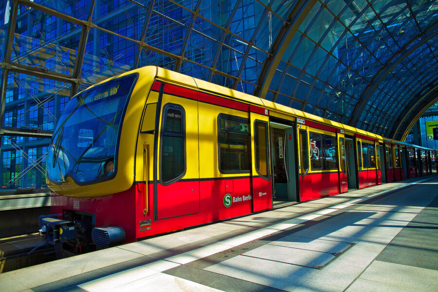 Modern Berlin S-Bahn train at a bright, spacious underground station with glass architecture.