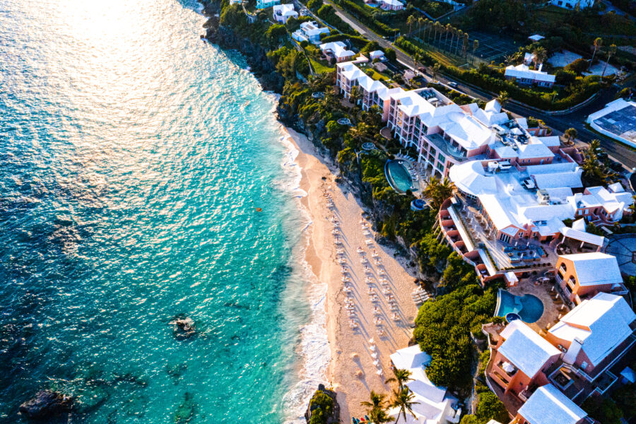 Aerial view of tranquil Bermuda, showcasing turquoise waters and lush greenery under a clear blue sky.