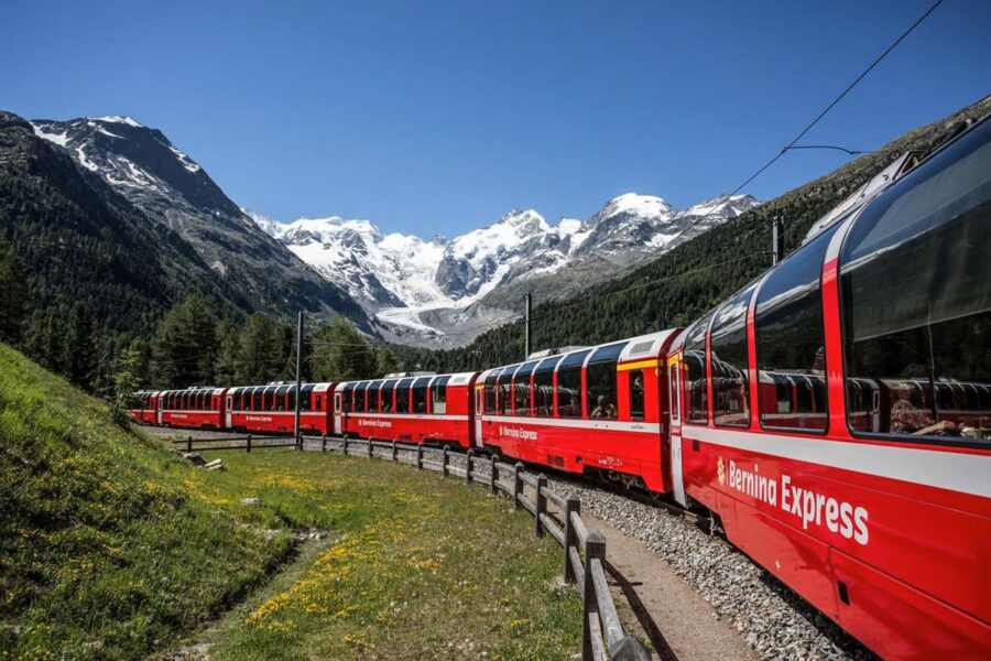 Bernina Express train through Swiss Alps: scenic mountains, lush greenery, iconic travel experience.