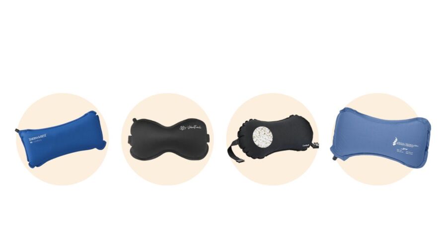 Four travel pillows are displayed against a light beige background. From left to right: blue rectangular, black bone-shaped, black with a white design, and blue curved.
