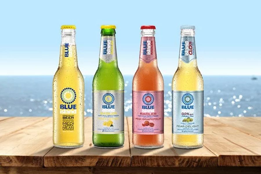 Blue Island beverage bottles with ocean view: Golden Lager, Natural Lemonade, Grapefruit Radler, Pear Delight.