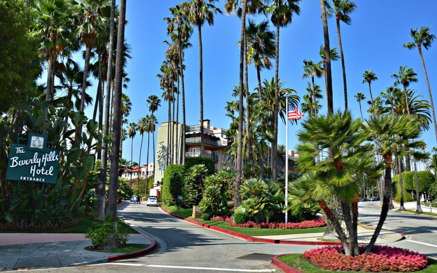 The iconic Beverly Hills Hotel entrance with palm trees, lush greenery, and classic architecture.