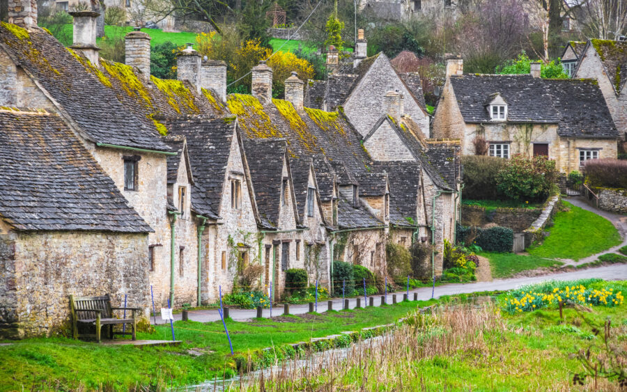 Charming Cotswold stone cottages nestled in the picturesque village of Bibury, England, surrounded by lush greenery