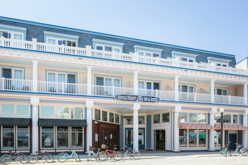 Bicycle Street Inn & Suites hotel front with balconies, shops, bikes, and coastal architectural design.