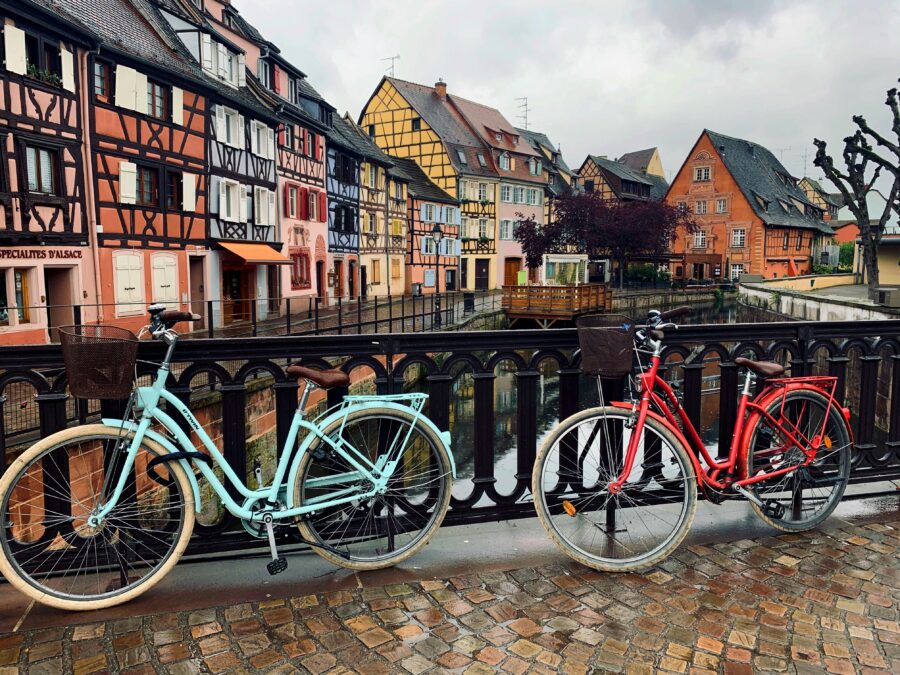 Bicycles on cobblestone bridge over Colmar Little Venice canal with half-timbered houses in France.