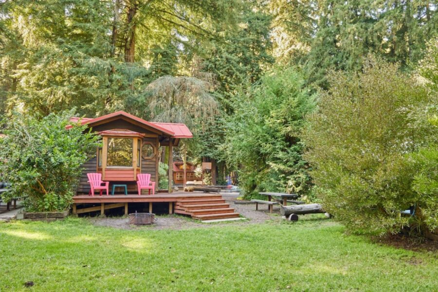 Cozy cabin in the woods featuring a deck and chairs, located at Big Sur Campground and Cabins.
