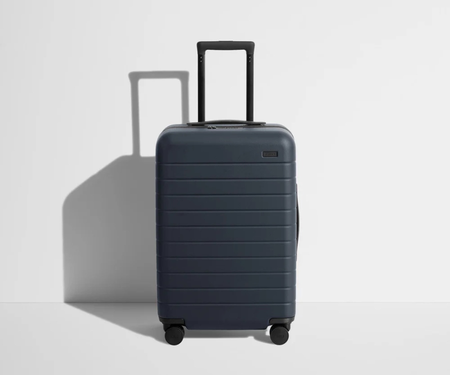 Navy blue Bigger Away carry-on suitcase with wheels on a white surface.