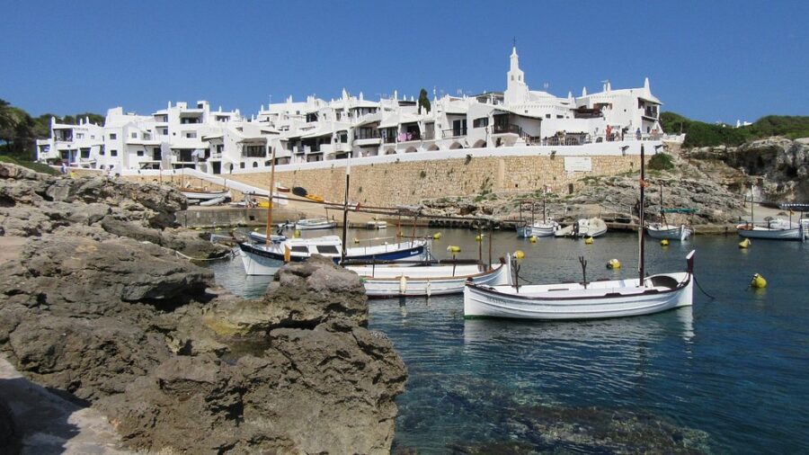 Scenic panorama of Binibeca, Menorca, featuring boats gently bobbing in the water.