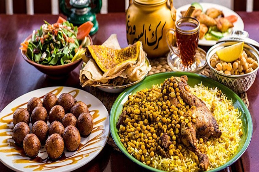 Middle Eastern feast with chicken rice, maamoul, salad, chickpeas, and tea.