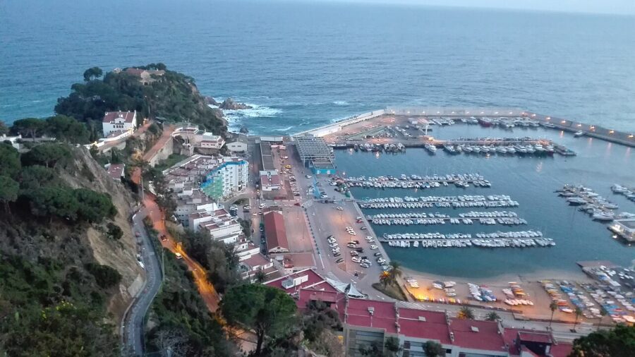 Several boats are moored in a picturesque harbor on the Costa Brava, Spain, reflecting the vibrant coastal scenery.