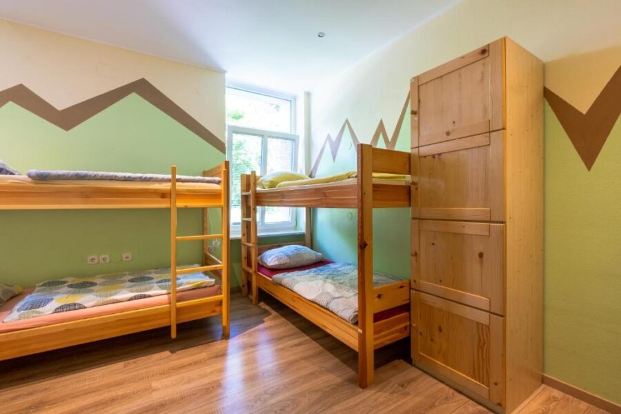 Bunk bed room at Bled Hostel featuring two bunk beds and a mountain-themed wall mural.