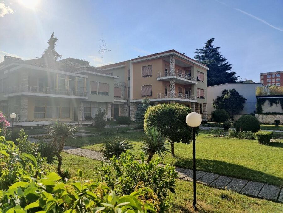 Sunny day in a Blloku, Tirana, Albania suburban neighborhood with two modern houses surrounded by a lush garden.