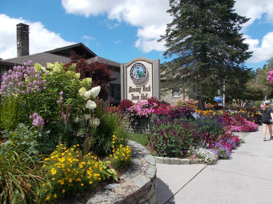 Blowing Rock Town Hall sign surrounded by vibrant flowers at the building's entrance.