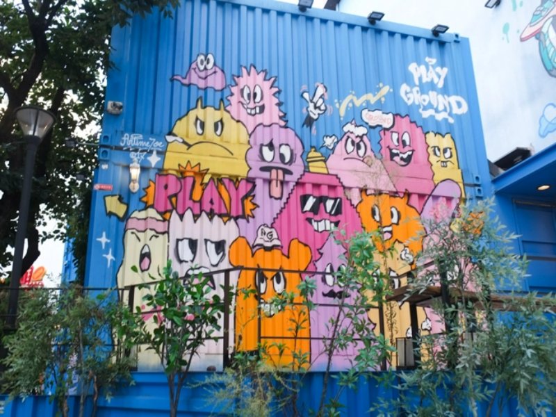 Hongdae blue container playground mural with colorful cartoon faces and street art.