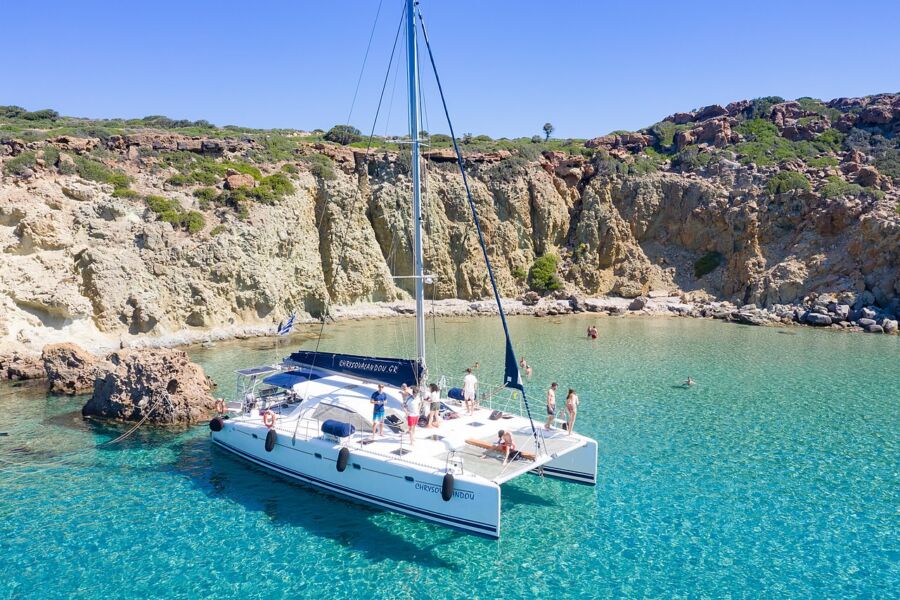 Catamaran sailing in vibrant blue waters, part of the Boat Trip Kleftiko, showcasing a tranquil maritime scene.