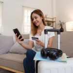 Asian woman using credit card booking flight tickets and hotel at home. Planning a trip and online booking, Summer vacation concept
