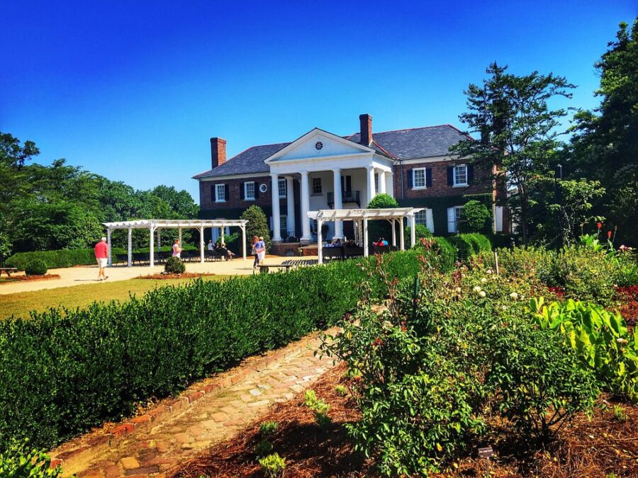 Boone Hall Plantation features a grand house with a wide front porch and a lush green lawn.
