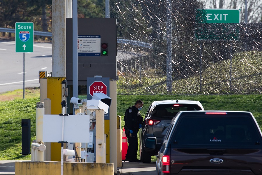 Border checkpoint inspection: law enforcement officer examines SUV at Interstate 5 crossing.