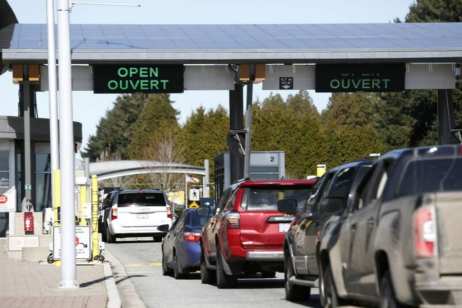International border crossing with vehicles, digital sign, modern architecture, and bilingual Open notice.