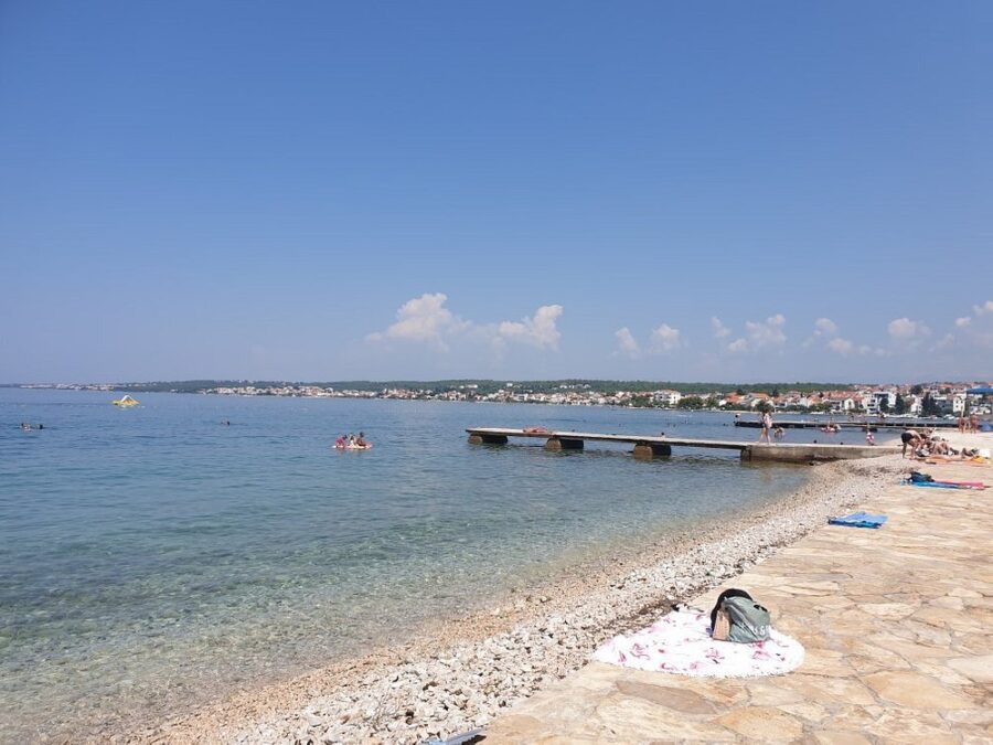 Borik Beach, Croatia, bustling with people enjoying swimming and sunbathing under the bright sun.
