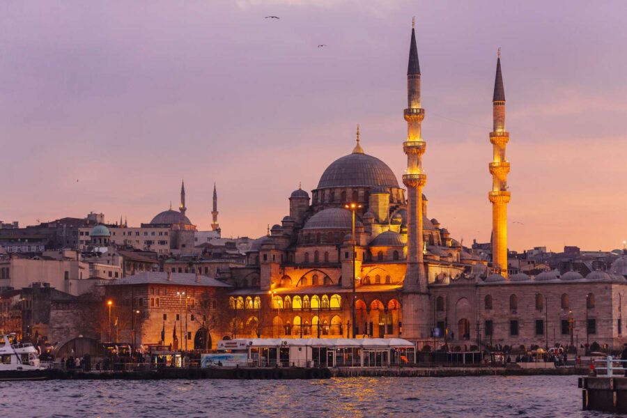 Iconic Istanbul mosque at sunset with reflections on water and twilight sky.