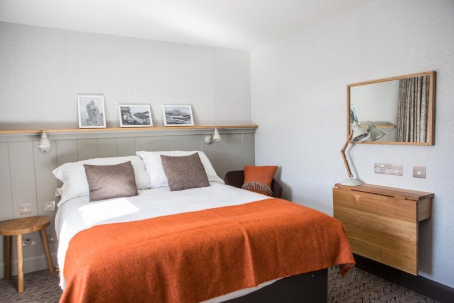 Interior of a Bosville Hotel bedroom showcasing a bed, desk, and mirror, creating a welcoming atmosphere.