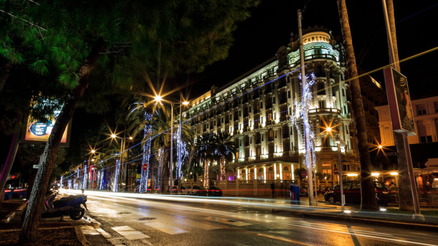 Night view of Boulevard de la Croisette in Cannes, France, illuminated by street lights and bustling with activity.