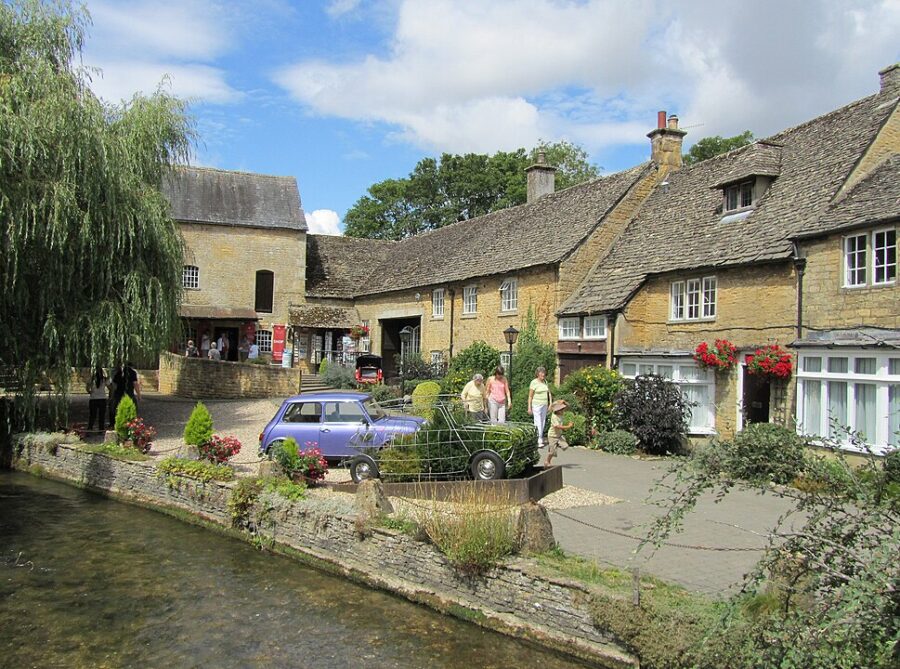 Bourton-on-the-Water, Cotswolds, a small river meanders past charming buildings in a picturesque town setting.