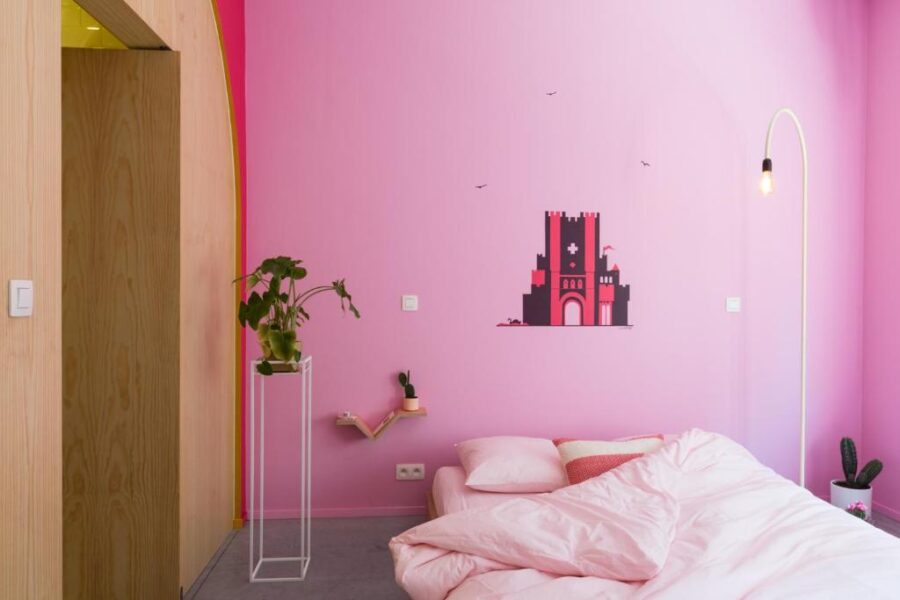 Cozy pink bedroom with a bed, pink walls, and a pink lamp, located in Boutique B&B Graaf, Ghent.

