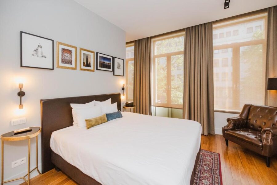 Cozy hotel room at Boutique Hotel Maison Emile featuring a bed, a chair, and decorative pictures on the wall.